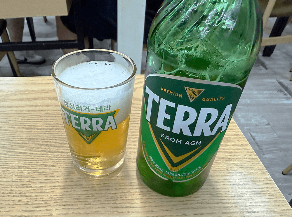 A beer in the glass and a green bottle of beer that called TERRA. there is the same logo as bottle on the glass too.