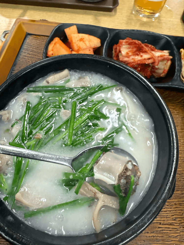 A slice of sundae is scooped by silver stainless spoon from the soup. Sundae's outside has white thin skin and inside is brown.